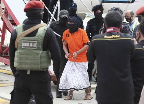 Polisi mengawal tersangka salah satu pimpinan jaringan Jemaah Islamiyah, Zulkarnaen (tengah), yang juga dikenal sebagai Aris Sumarsono, setibanya di Bandara Internasional Soekarno-Hatta di Tangerang, Banten, 16 Desember 2020. [AP]