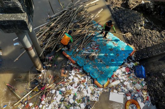 Pekerja memindahkan berbagai barang limbah kayu dan plastik dari sebuah sungai di Jakarta pada 22 April 2020 – atau dikenal sebagai Hari Bumi. [AFP]