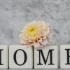 Dekorasi rumah yang stylish menampilkan huruf-huruf yang mengeja 'HOME' dengan aksen dahlia yang lembut untuk menciptakan suasana yang nyaman.