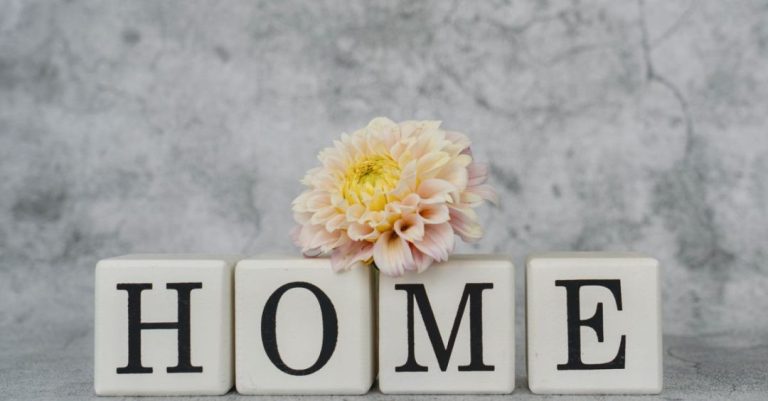 Dekorasi rumah yang stylish menampilkan huruf-huruf yang mengeja 'HOME' dengan aksen dahlia yang lembut untuk menciptakan suasana yang nyaman.