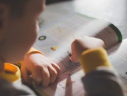 Seorang anak kecil yang fokus pada buku mewarnai, meningkatkan pembelajaran dan kreativitas.