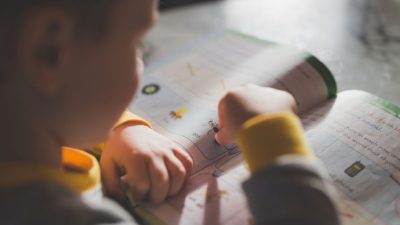 Seorang anak kecil yang fokus pada buku mewarnai, meningkatkan pembelajaran dan kreativitas.